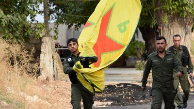 Syrian Kurdish fighters walk carrying a People's Protection Units (YPG) yellow flag in the Syrian Kurdish town of Kobane. AFP