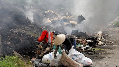 A woman collects recyclable items from electronic equipment at a garbage dump near a rice field in Vinh Phuc province, Vietnam. REUTERS
