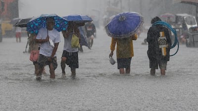 Filipinos walk through floodwaters in Malabon City, north of Manila. Rolex De La Pena / EPA