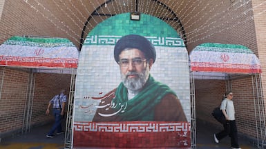 Commuters walk past a large tiled image of Iran's leader Ayatollah Mojtaba Khamenei at the entrance to the metro in Tehran on May 9. AFP