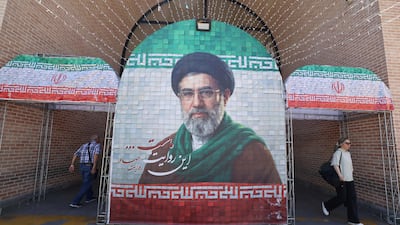 Commuters walk past a large tiled image of Iran's leader Ayatollah Mojtaba Khamenei at the entrance to the metro in Tehran on May 9. AFP