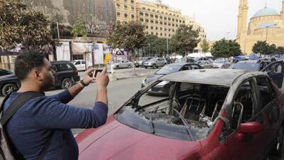 A Lebanese man takes pictures of a damaged car after a night of clashes between supporters of the Shiite groups Hezbollah and Amal and anti-government demonstrators in the capital Beirut. AFP