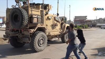 In this frame grab from video provided by Hawar News, ANHA, the Kurdish news agency, residents who are angry over the U.S. withdrawal from Syria hurl potatoes at American military vehicles in the town of Qamishli, northern Syria. AP