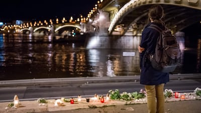 A woman stands by flowers and candles placed on the riverbank to pay tribute to the victims of the capsized boat at Margaret Bridge, in Budapest, Hungary. EPA