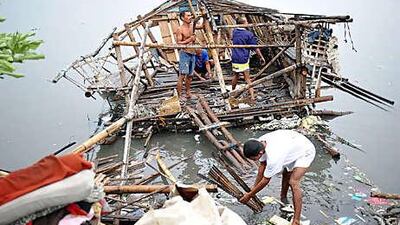 Residents try to salvage their damaged shanty yesterday along the coastal road in Paranaque in suburban Manila.