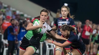 A Harlequins player runs with the ball as a Dubai College player attempts a tackle.