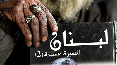 Mohammed Maghrabi holds a book that reads 'Lebanon' in Arabic.