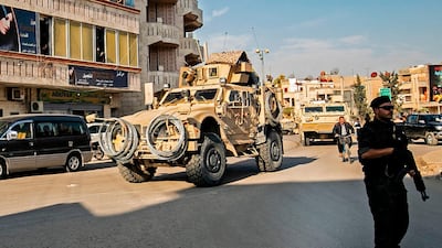 A member of the Syrian Democratic Forces (SDF) stands on the side of a road as US military vehicles drive, east of the Kurdish-controlled northeastern Syrian city of Qamishli on November 13, 2019. AFP