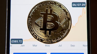 A November 2017 file photo showing a gold plated souvenir Bitcoin coin on an app for the digital asset broker, Coinbase. Coinbase, an exchange for bitcoin and other cryptocurrencies, filed papers on February 25, 2021 to become publicly traded. AFP