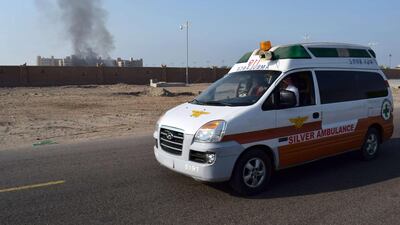An ambulance drives as smoke billows from the Al-Qasr hotel. Saleh Al-Obeidi / AFP