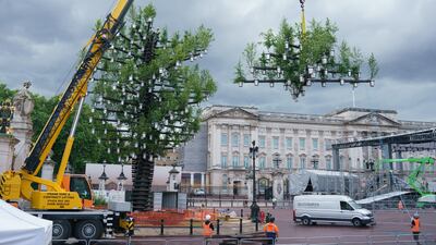 Platinum jubilee preparations were in full swing on Tuesday as construction workers positioned the Queen's Green Canopy Tree of Trees sculpture outside Buckingham Palace, London. PA