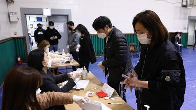 South Koreans wear masks and plastic gloves as they queue up to cast their ballots for the Parliamentary election in Seoul, South Korea. Getty