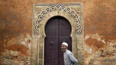 A man walks in front of doors in a wall of Rabat’s Medina.