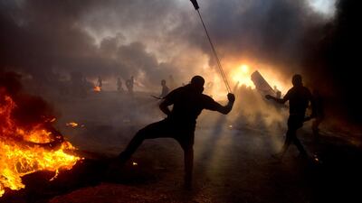 Black smoke from burning tyres hangs in the sky as Palestinian protesters hurl stones towards troops during a protest at Gaza's border with Israel. AP