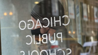 A person wearing a face mask stands at the entrance of the headquarters for Chicago Public Schools. AFP