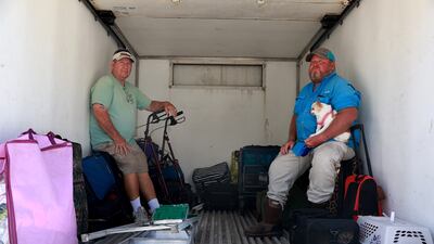 Charlie Russell and Brian Lewis and pup ride in the back of a lorry to a boat off Pine Island. Getty / AFP