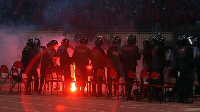 Egyptian riot policemen stand guard as a flare is thrown during a football match between Al Masry and Al Ahly at Port Said, where at least 74 people were killed and hundreds injured when rival fans clashed after the football match on February 1, 2012. AFP