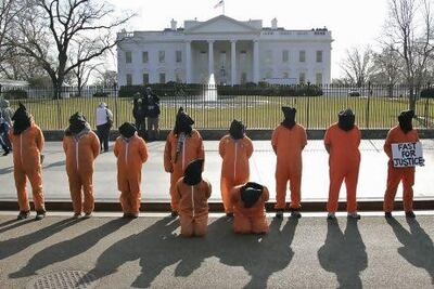 Human rights activists, hooded and wearing orange prison garb to represent prisoners at Guantanamo Bay, Cuba, protest in front of the White House. AFP