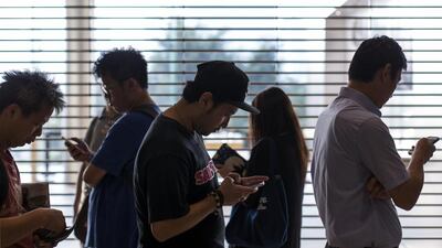 Customers look at their mobile phones while waiting in line outside an Apple Inc store ahead of the company’s iPhone 6 and iPhone 6 Plus launch in Hong Kong. Jerome Favre / Bloomberg
