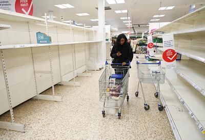A woman pushes her trolley down empty toilet roll shelves in a supermarket in London. EPA