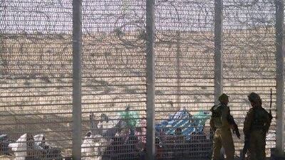 African refugees sit on the ground behind a border fence after they attempted to cross illegally from Egypt into Israel as Israeli soldiers stand guard near the border with Egypt.
