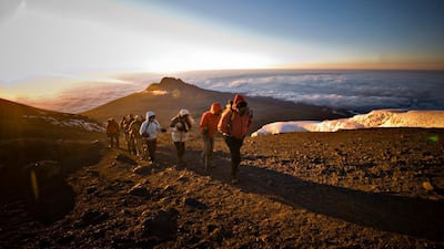 A team of hikers approach the summit of Mt. Kilimanjaro at sunrise. Getty Images
