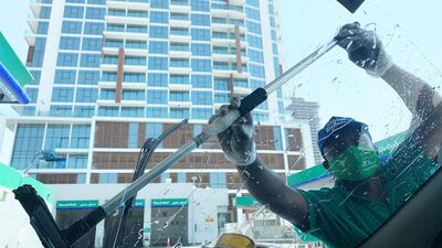 A petrol station attendant wears a face mask in Dubai. Pawan Singh / The National