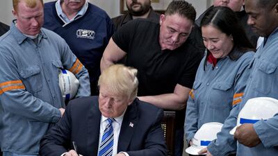 Donald Trump signs a proclamation on adjusting imports of steel into the US next to steel and aluminum workers in the Roosevelt Room of the White House. Andrew Harrer / Bloomberg