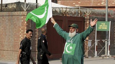 Policemen pass by a Pakistan cricket fan outside Gaddafi Stadium while the Zimbabwe team practice ahead of the cricket series between Pakistan and Zimbabwe starting on Friday. Mohsin Raza / Reuters