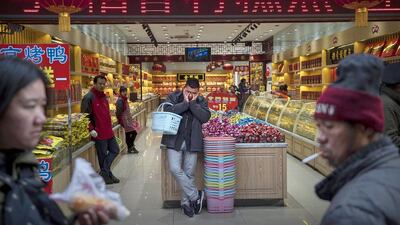 A Chinese customer rests as he stands in a store in a shopping district in central Beijing. China’s economic growth slowed to its weakest point in years to 7.4 per cent. Kevin Frayer / Getty Images