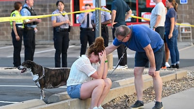 A passerby comforts a woman as she sits on a street corner near the shooting site at the Annunciation Catholic School in Minneapolis, Minnesota, on August 27. Two children were killed and 17 others wounded before the gunman took his own life. EPA