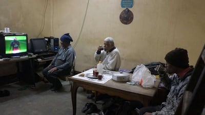 From left, brothers Gamal, Hashim and Mahmoud Abdelmeniem drink tea as they watching a football match on television at their house on the rooftop of a building in Cairo.