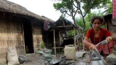 A Bhutanese refugee cleans utensils while others, below, collect water at the Beldangi camp, some 300km south-east of Kathmandu.