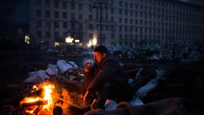 An anti-government protester warms himself by a fire on a barricade in Kiev. Martin Bureau / AFP Photo