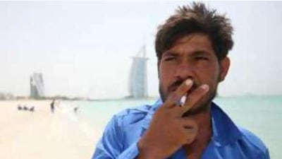 Sherbahader, a Pakistani labourer, enjoys a cigarette during midday break at Jumeirah Beach.