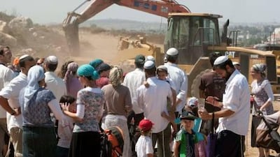 Israeli settlers gather near building machinery at the construction site of 50 housing units in the West Bank settlement of Ariel. The site will house former residents of the Gush Katif settlements that were dismantled in 2005 in the Gaza Strip.