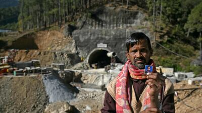 A father of one of the trapped construction workers with a picture of his son. AFP
