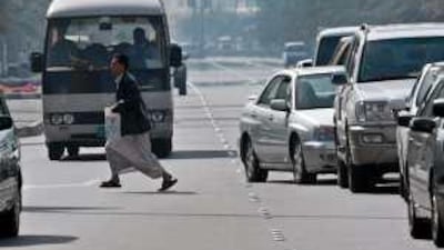 A pedestrian dashes across a busy road in the middle of traffic in Abu Dhabi.