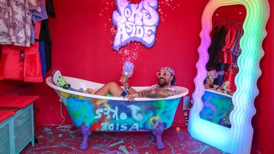 Ibrahim Abudyak poses for a photo in a bathtub of colourful balls
