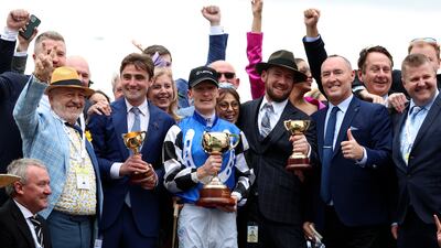 Jockey Mark Zahra, centre, holds his trophy as he celebrates with connections after winning the Melbourne Cup horse race on Gold Trip in Melbourne, Australia. AP Photo