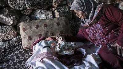 A displaced Syrian woman comforts her one-month old grandchild Fatima inside a stone house near Kafer Rouma, Syria. AP Photo