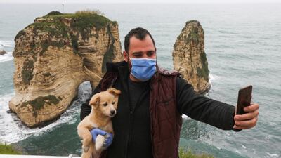 A man takes a selfie while carrying a dog in front of the Pigeons Rock in Beirut, Lebanon. Reuters