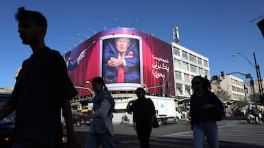 Iranians walk past an anti-Trump billboard on a street in Tehran. EPA