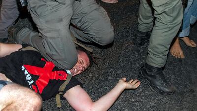 An Israeli police officer puts his knee on a demonstrator to make an arrest during a protest against Israel's Prime Minister Benjamin Netanyahu outside his residence in Jerusalem. AP Photo