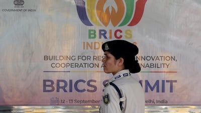 A police officer stands in front of a hoarding at Bharat Mandapam, the venue for the Brics summit in New Delhi. Reuters