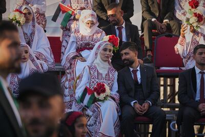 Palestinian couple Hikmat Lawwa and Eman Lawwa, centre, join other newlyweds at Hamad City in Khan Younis. AP
