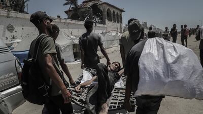 Palestinians move an injured man after gathering to collect food from a humanitarian aid distribution point in Beit Lahia, northern Gaza, on Sunday, July 20. Bloomberg
