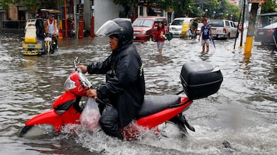 A scooter rider drives through the water. AP Photo