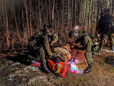 Polish servicemen deliver medical support and transport a migrant on the border with Belarus. Reuters