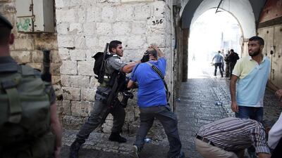 Israeli photographer Menahem Kahana (C) is roughed up by an Israeli policeman during a demonstration in a street in the Muslim quarter of Jerusalem's Old City, on October 4, 2015. It came as Israel took the rare and drastic step of barring Palestinians from the Old City. Thomas Coex/AFP Photo